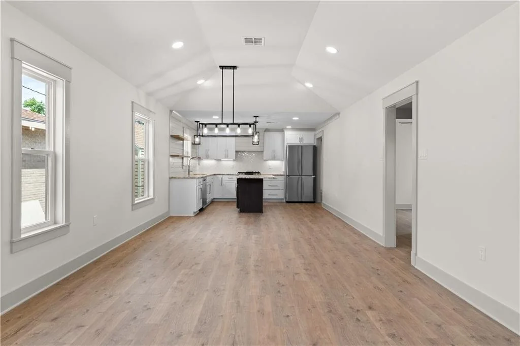Renovated living room with wood flooring opening into a white kitchen